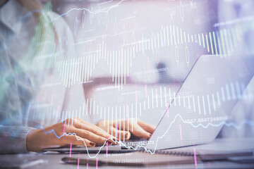 Double exposure of woman hands working on computer and forex graph hologram drawing. Financial analysis concept.
