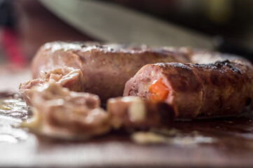 sausage on cutting board with blurred knife in the background