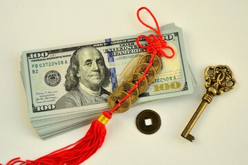 A bundle of 100 dollar bills, a key, and сhinese feng shui coins  talismans to attract wealth and success