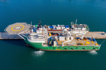 Offshore supply Ship docked next to a general Cargo vessel, Aerial image.