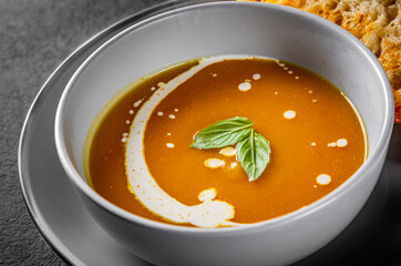Pumpkin soup in bowl on Dark grey black slate background