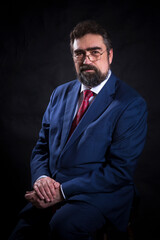 Mature businessman dressed in blue suit with red tie studio portrait.