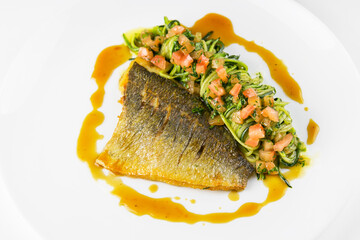 Dorado fish fillet with vegetables on a white dish