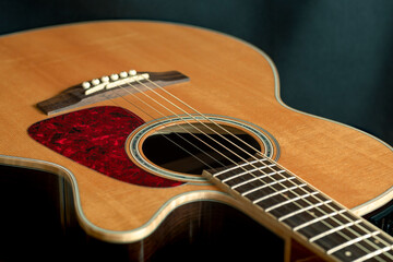 acoustic guitar with top made of spruce wood with cutaway closeup on dark background