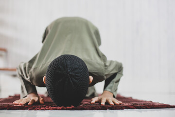 Asian Muslim Boy doing Salat with prostration pose on the prayer mat
