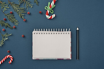 New Year's decor and a notebook in the center on a blue background. Christmas decoration. Copy space, flat lay, mock up, top view.