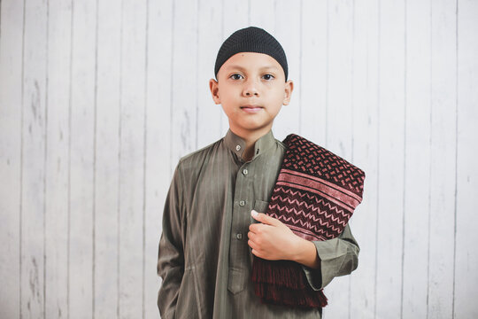 Portrait asian Muslim Boy wearing traditional costume called gamis  looking at camera get ready to pray