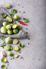 fresh small brussels sprouts with herbs and peppers on a gray table