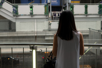 Female woman is waiting in the rain at the subway train transit platform