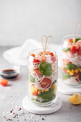 rice noodles with shrimps and vegetables in a glass jar on a white table