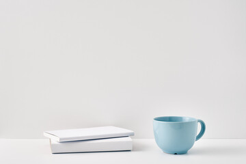 The mug stands on a stack of books on a white background. Natural and eco-friendly materials. Copy space, mock up