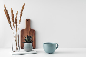 A mug, a potted houseplant, a clear vase and a wooden cutting board. Eco-friendly materials in the decor of the room, minimalism. Copy space, mock up