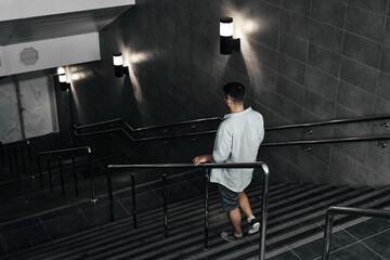 Fototapeta na wymiar A young guy comes down the stairs, an underground passage. Subway, stairs down.
