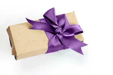 Gift box wrapped by kraft brown paper with beautiful purple satin ribbon. Universal gift design for...