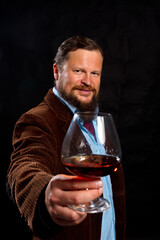 Stylish bearded man dressed in brown jacket with glass of whisky