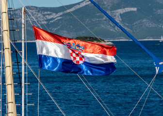 Croatian flag on the mast of the yacht flutters in the wind on the background of the sea and...
