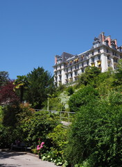 Luxury hotel and park in european Montreux city in canton Vaud in Switzerland, clear blue sky in 2017 warm sunny summer day on July - vertical.