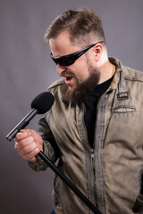 Bearded emotional rock singer with microphone studio portrait.