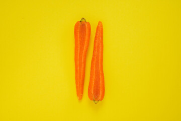 Carrot cut in half on yellow background. Healthy vegetarian food.