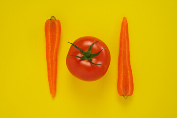 Carrot and tomato on yellow background. Healthy vegetarian food.