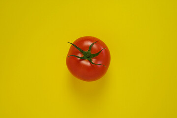 Tomato on yellow background. Healthy vegetarian food.