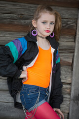 Little red-haired girl in bright clothes with makeup on her face. A child in the style of the nineties.