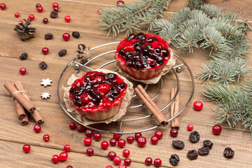 Fototapeta na wymiar Berry muffins on metal tray. Cinnamon sticks, raisins and cranberries on table. Fir branches