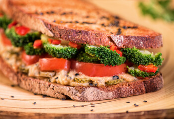Super food sandwich vegan with chickpea hummus, sesame, tomatoes and broccoli, on wholemeal bread. Idea of healthy food.