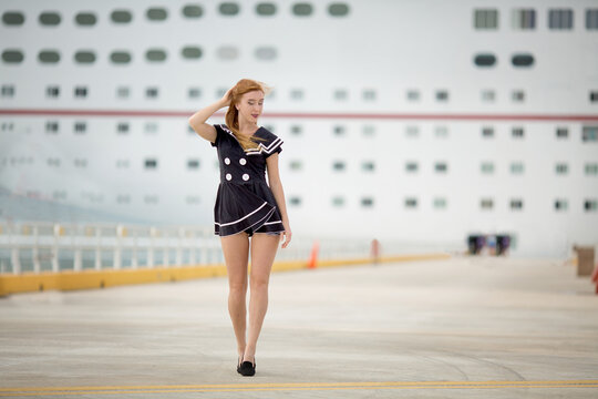 red hair sailor girl in port happy poses with cruise ship  and ocean on background, travel photo content