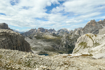 A panoramic view on Dolomites in Italy. There are sharp and steep mountain slopes around. At the...