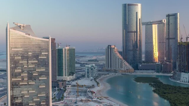 Buildings on Al Reem island in Abu Dhabi timelapse from above. Aerial citiscape of Al Reem Island at evening, showing the reflection of sun in skyscrapers and long shadows.
