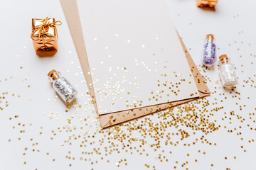Blank note with envelope, gifts and gold glitter stars on white background