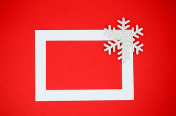 White frame and snowflakes on a red background. New year's winter card. Christmas flat lay. Minimalism, minimalistic, geometry.