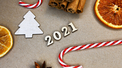 2021 year on craft background with candy canes, cinamon, wooden fir trees, and dry oranges. New year concept. Festive concept. Happy new 2021 year. Background for post card.