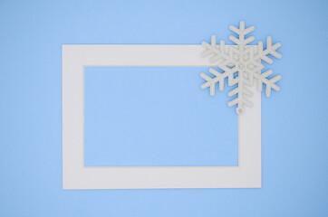 White frame and snowflakes on a blue background. New year's winter card. Christmas flat lay. Minimalism, minimalistic, geometry.