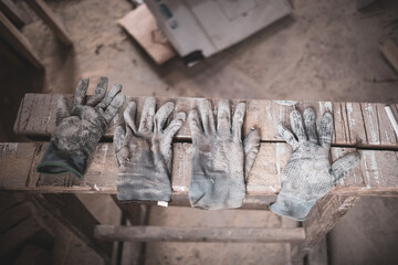 Obraz premium 4 used, dirty work gloves lying side by side on a wooden board on a construction site