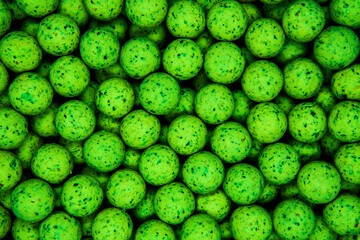 Small, sweet green balls. Round boilies used as carp fishing bait. Abstract green background