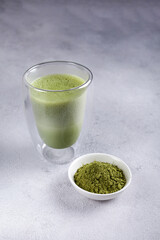 Matcha with milk in a glass on a light background