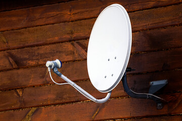 Satelite is attached to the wall of the wooden house..