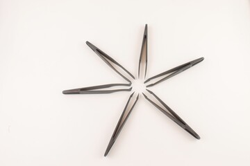 Black plastic tweezers, black star isolated on a white background