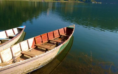 fishing boat in a lake water, old wooden boat, wooden boat in a still lake water.