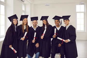 Group of young happy university graduates multiethnic friends with diplomas in hands