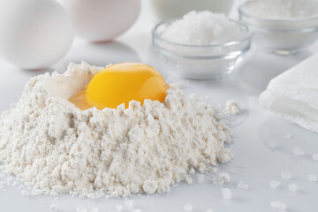flour, egg yolk, salt, sugar, milk on a white table.