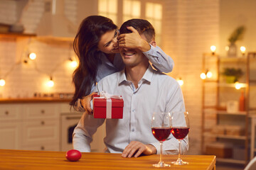 Smiling pretty brunette woman covering boyfriends eyes and making present surprise