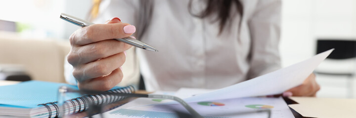 Metal handle in female hand close-up. On table are glasses, documents, paper with diagrams and notebook. Business assistance.