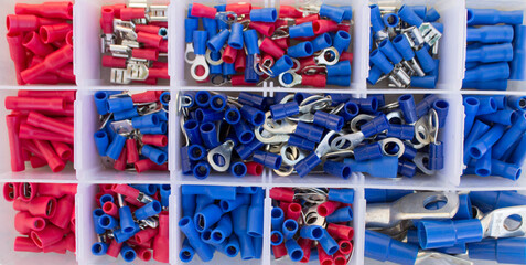 flat lay of electrical terminals assortment kit arranged in plastic box. Colored crimping equipment...