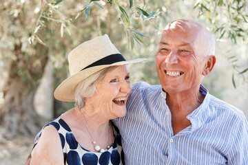 Coppia di anziani  felice si abbraccia sorridente in un parco all'aperto
