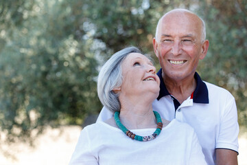 Coppia di anziani  felice si abbraccia sorridente in un parco all'aperto