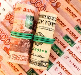 American dollars and Russian rubles rolled up in a tube. Currency exchange rate. Ruble devaluation concept. Money background. Selective focus.