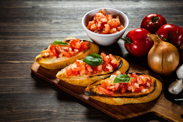 Bruschetta with ingredients on cutting board on wooden background
